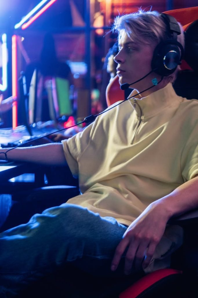 Focused gamer with headphones, immersed in high-tech gaming environment.