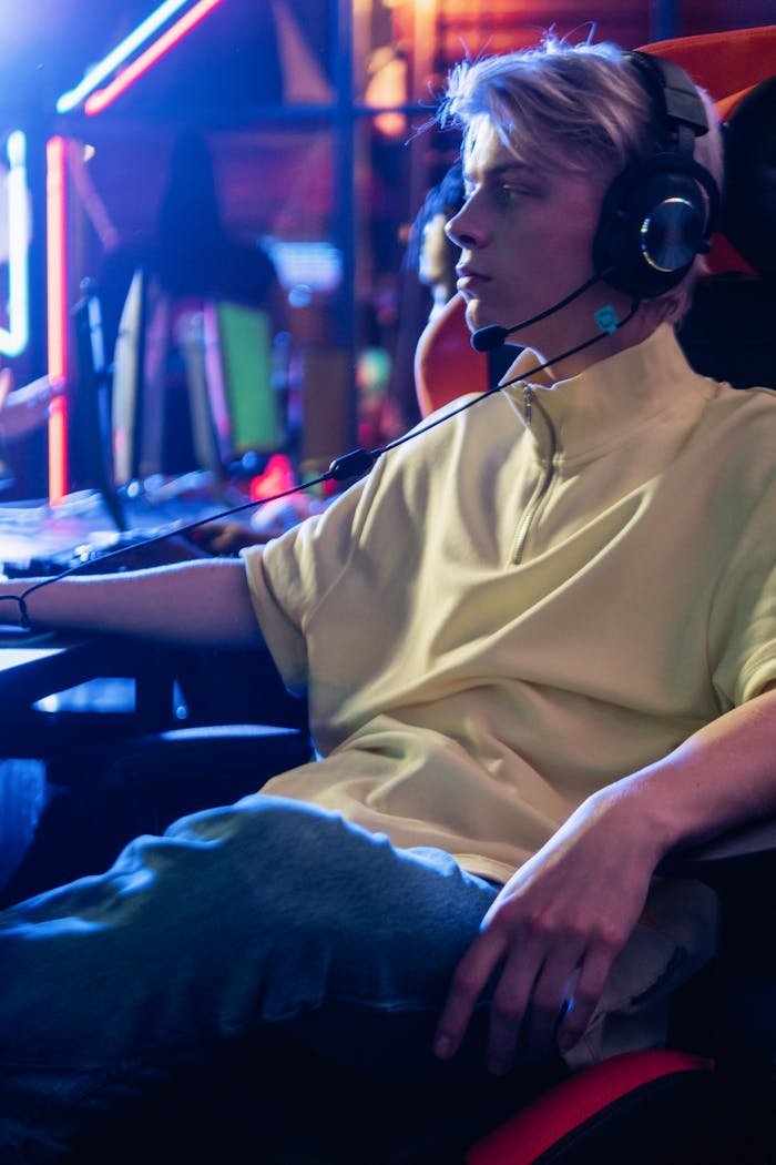 Focused gamer with headphones, immersed in high-tech gaming environment.